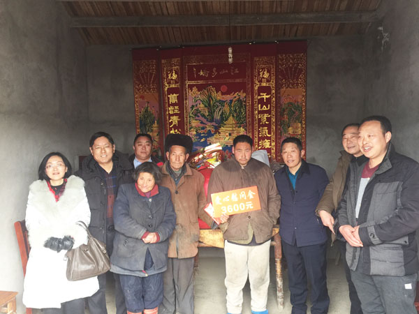 商會會長熊桂祥（左二）、監事會主席李榮杰（右二）和萬盛合作社董事長張世和（左一）、總經理王喜本（右一）帶著慰問團正在慰問張澤俊全家（圖中），并與他們合影留念